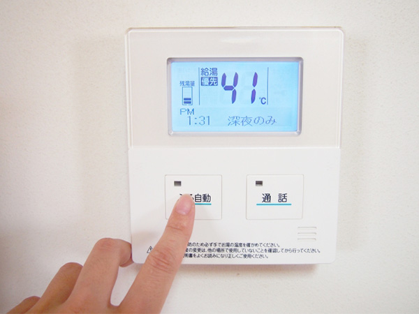 給湯器リモコンを指で押す様子